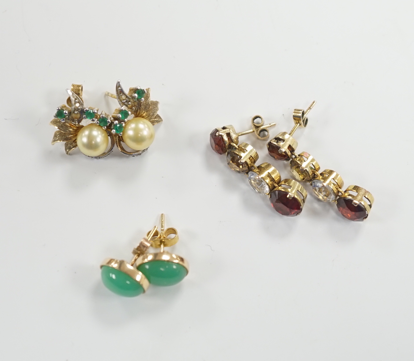 A pair of 1950’s emerald and cultured pearl cluster set earrings, 17mm, a pair of yellow metal and four stone drop earrings and a pair of cabochon chrysoprase ear studs, gross weight 10.3 grams.